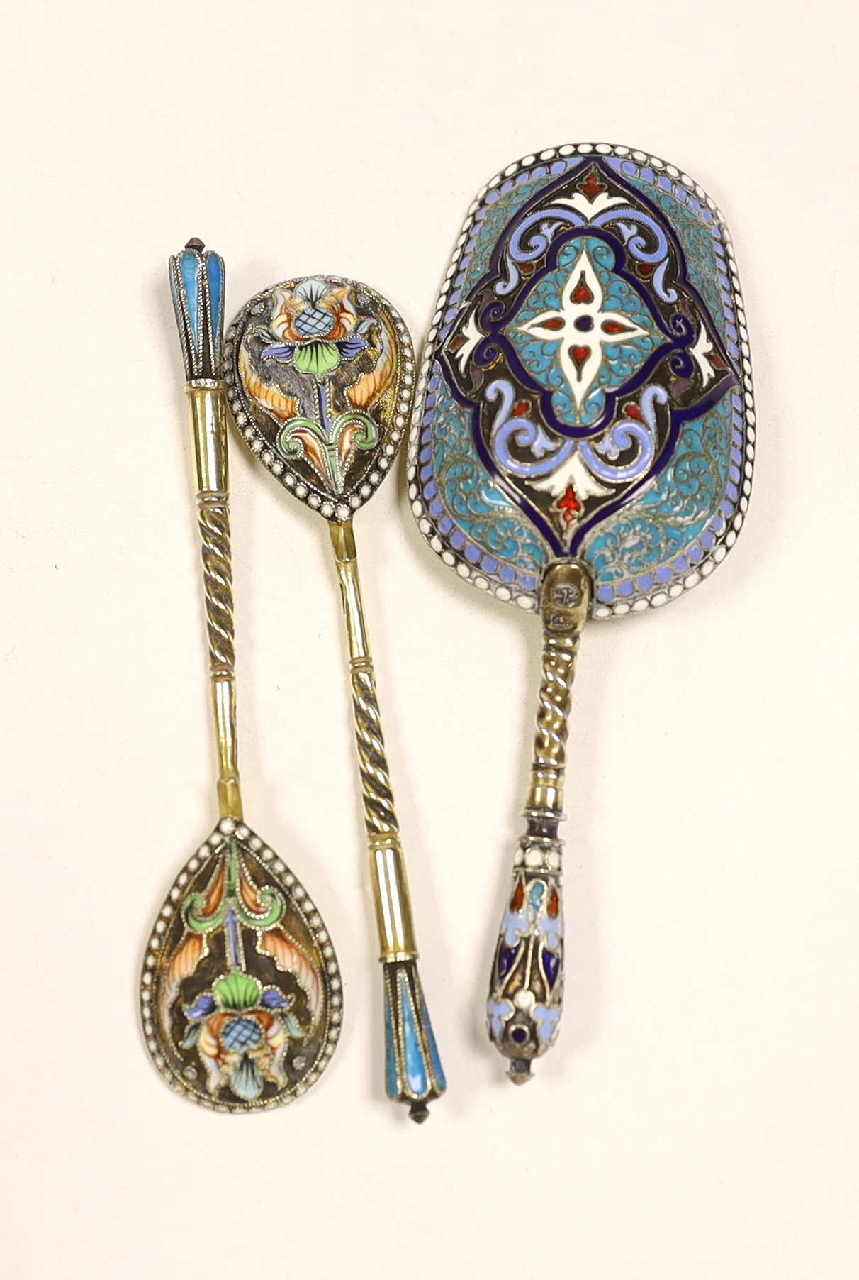 A late 19th century Russian 84 zolotnik and polychrome cloisonné enamel shovel shaped spoon, assay master Anatoly Artsibashov?, Moscow, 1891, 10.6cm, two later Russian similar coffee spoons and a cased 1911 commemorative
